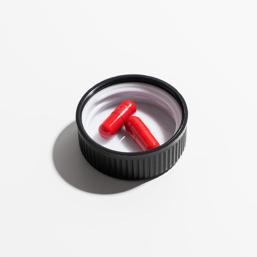 A picture of two capsules place inside the cap of a Zantrex bottle featured on a white background