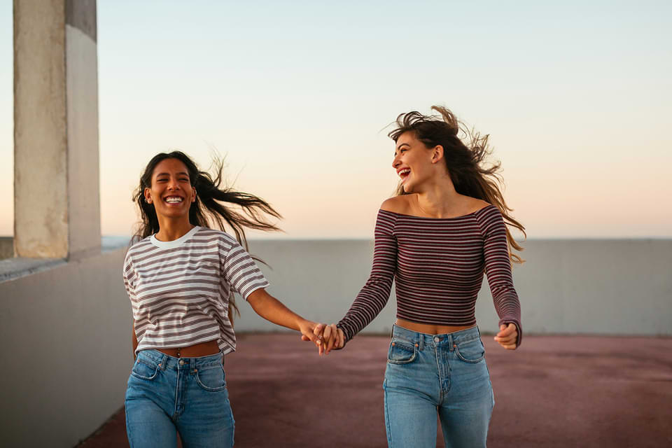 Two women holding hands and laughing.