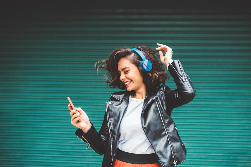 Woman with headphones and leather jacket dancing.